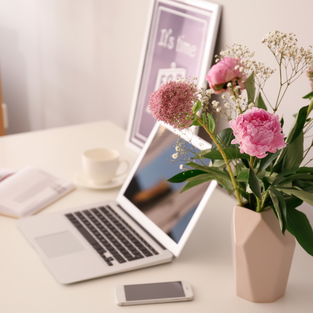 laptop on desk with pink roses in vase
