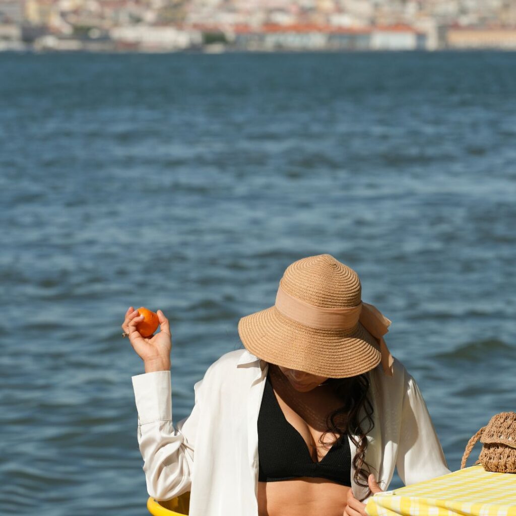 woman-wearing-hat-eating-apple-on-water